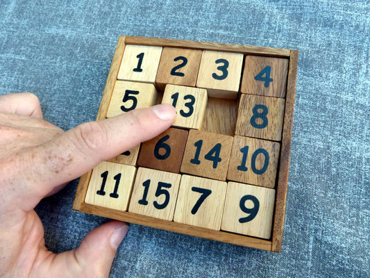 Schiebespiel aus Holz mit 15 quadratischen Teilen die in einem Rahmen geschoben werden können