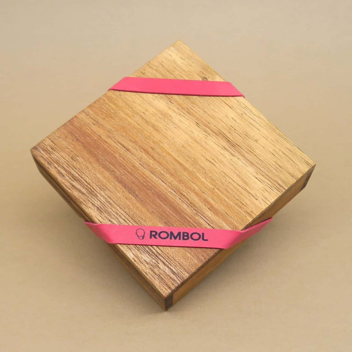 Quadratische Holzbox eines IQ-Puzzles, schräg aufgestellt und von einem rotem Band zusammengehalten.
