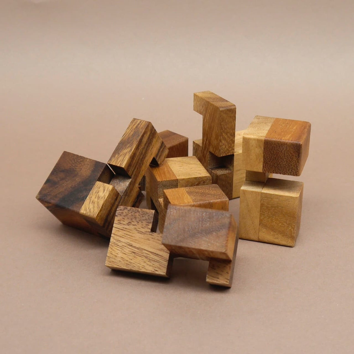 Holzwuerfel: lose verstreute Puzzleteile aus unterschiedlich gemasertem Holz liegen ungeordnet auf dem Tisch.