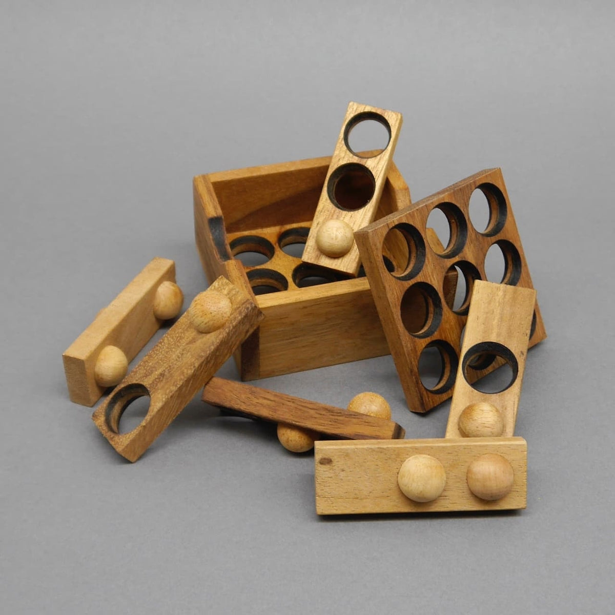Geöffnete Box mit verstreuten Stäben, Scheiben und Kugeln des 9‑Loch‑Logikpuzzle, bereit zum neuen Zusammenbau.