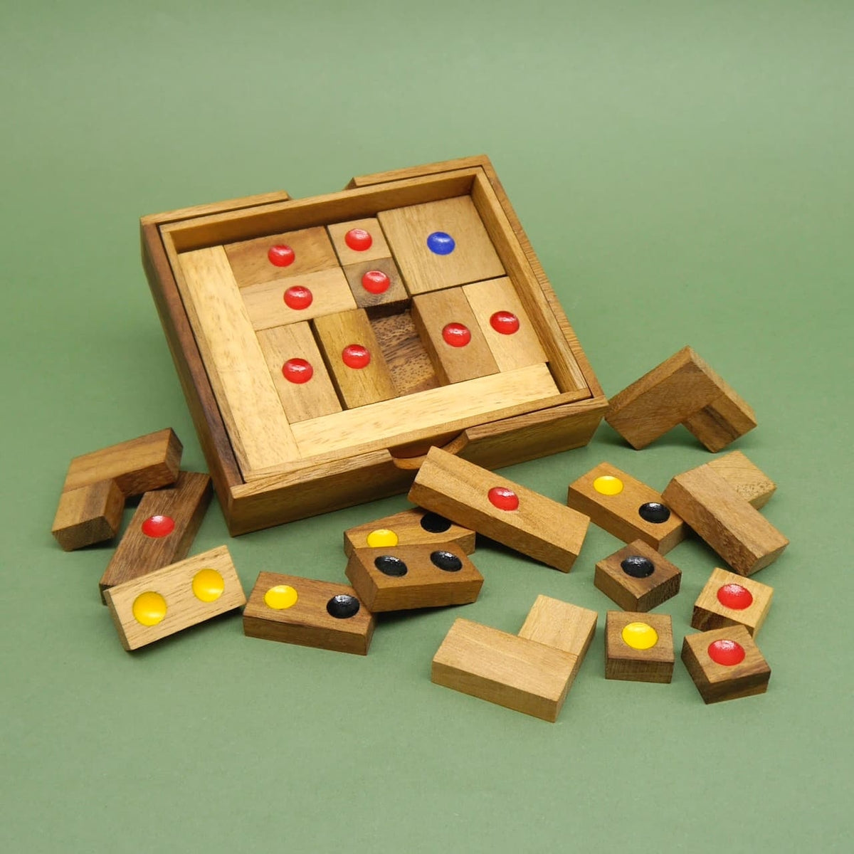 Offenes Holz‑Spieleset: quadratisches Puzzle mit bunten Punkten, zahlreiche weitere Teile liegen rundherum auf dem Tisch.