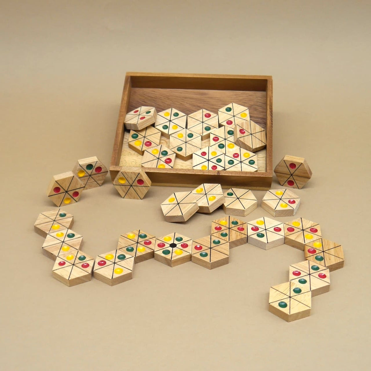 Beim Spieleabend verstreute Ampel-Domino-Spielsteine, die sich vom offenen Holzkasten in einer bunten Reihe über den Tisch schlängeln.