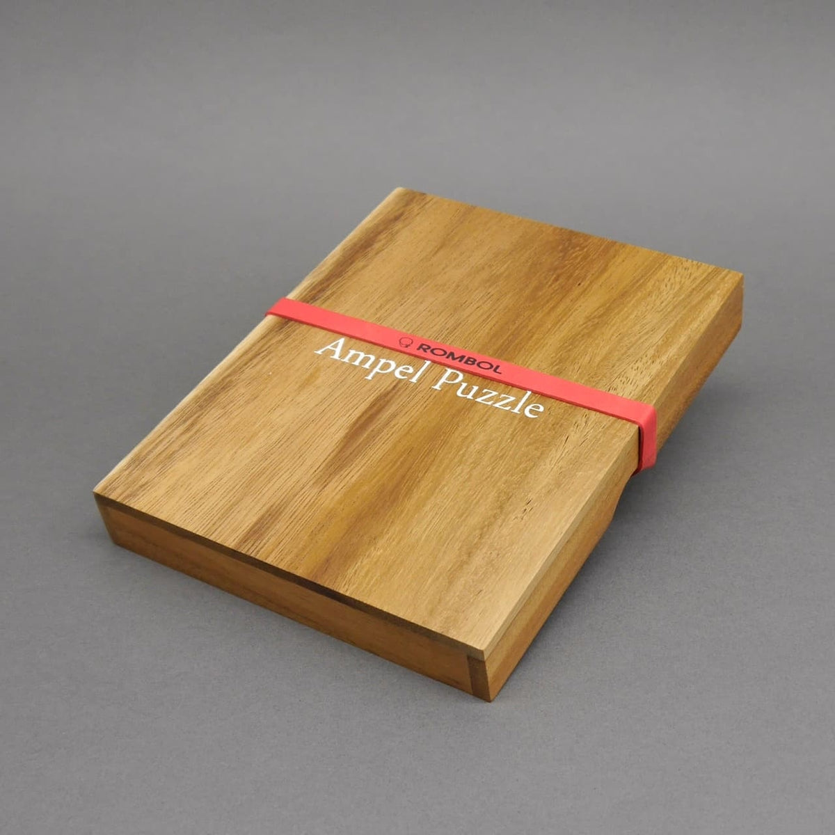 Legepuzzle-Box: Geschlossenes Ampel Puzzle aus glattem Holz, von einem roten Gummiband zusammengehalten.