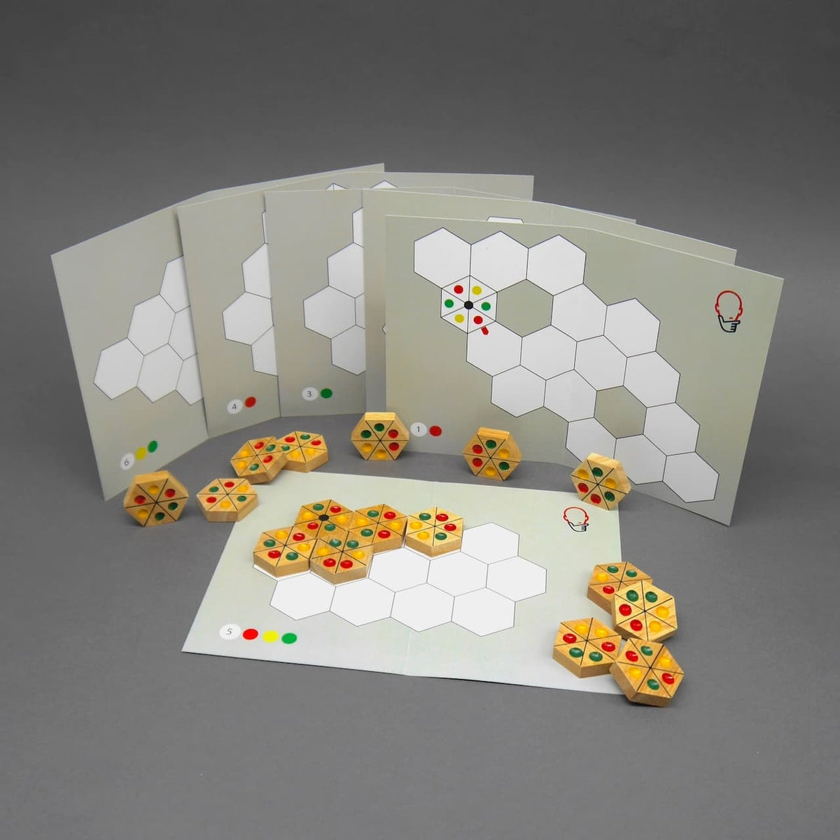 Rätsel-Karten des Ampel Puzzle stehen fächerförmig; davor liegen farbige Holzsteine zum Auslegen.