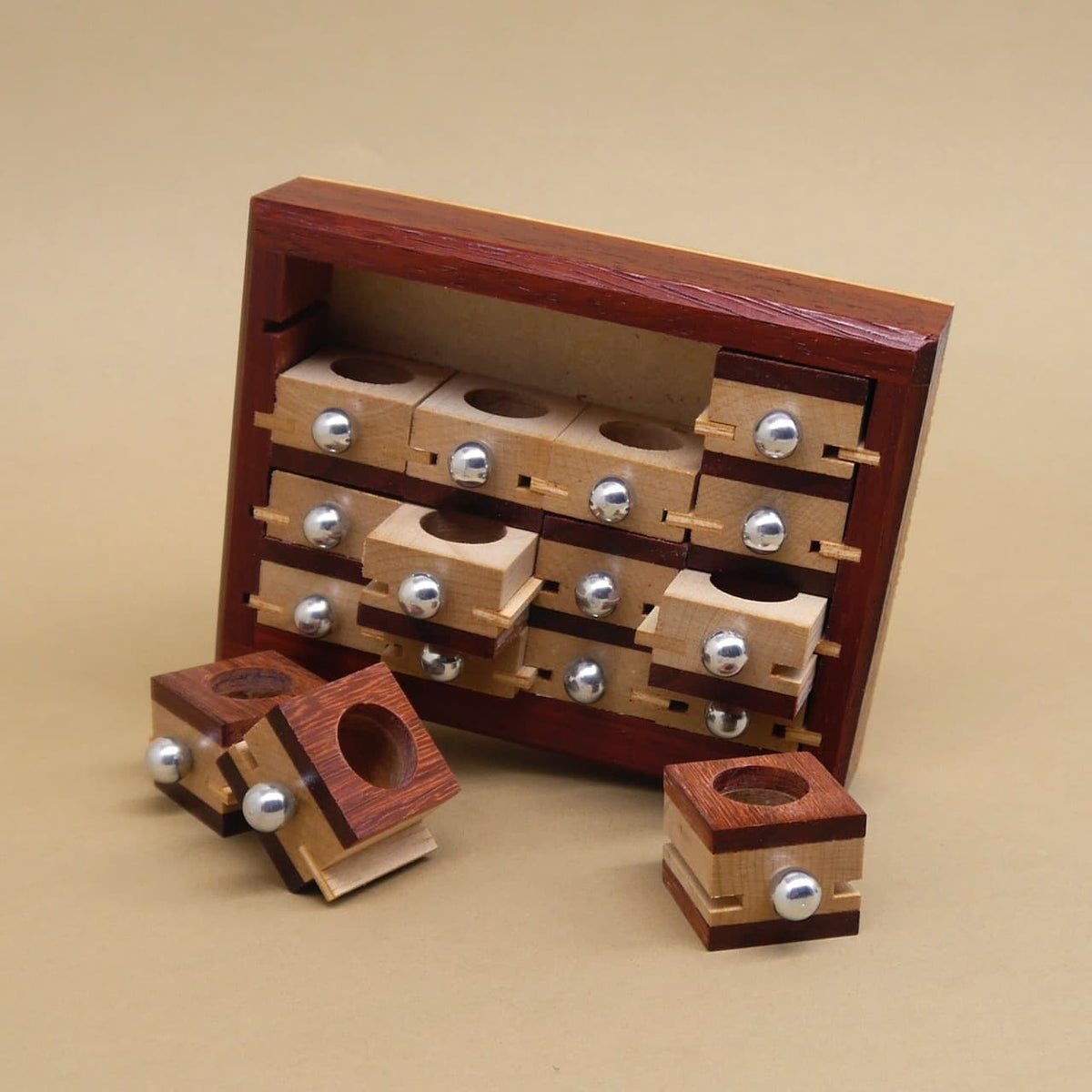 Holzpuzzle mit entnommenen Würfeln, die vor dem Puzzle liegen; im Hintergrund sind die leeren Fächer des Apothekerschranks sichtbar.