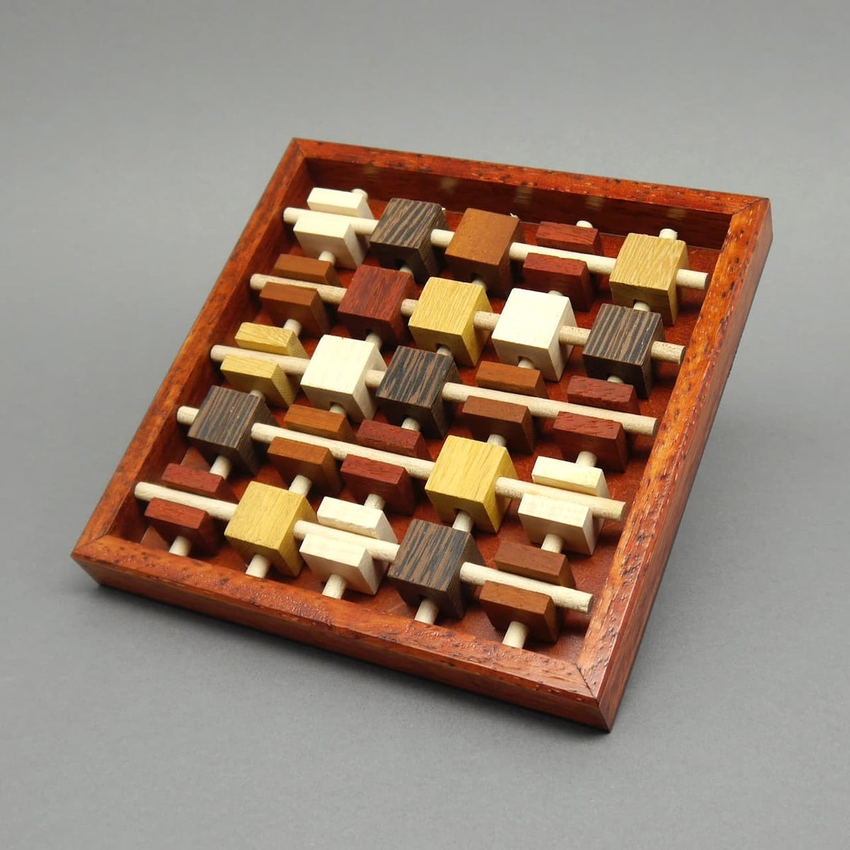 Detailansicht des hölzernen ‚Brochettes‘-Puzzles, bei dem mehrere Stäbe und Holzteile ineinander gesteckt werden müssen. Ein herausforderndes Puzzle, speziell für Erwachsene entwickelt.