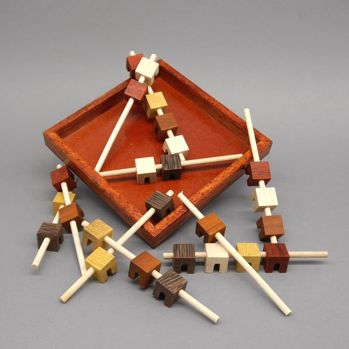 Das hölzerne Rätselspiel ‚Brochettes‘, bestehend aus individuell gestalteten Holzteilen, die in einer bestimmten Reihenfolge verbunden werden. Ein Logikspiel für Geduld und Konzentration.