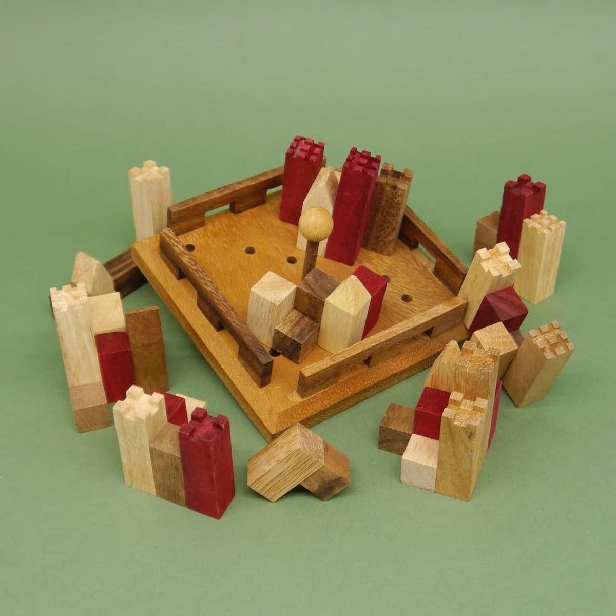 Naturfarbene und rote Holztürme säumen eine teilbestückte Basisplatte; das Castle-Puzzle zeigt seine Burgteile locker um das Spielfeld verteilt.