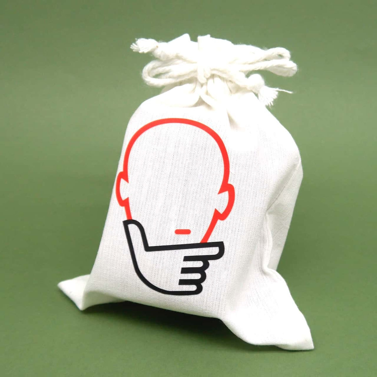 Weißer Stoffbeutel mit stilisiertem Kopf-und-Hand-Logo, verpackt für ein handliches Holzpuzzle.