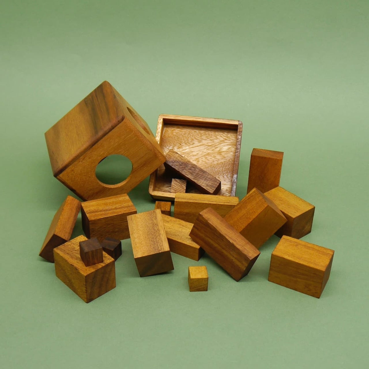 Zerlegtes Puzzle aus Holzklötzen mit kubischer Hülle und Ablagebrett, die Teile sind locker über die Fläche verstreut.