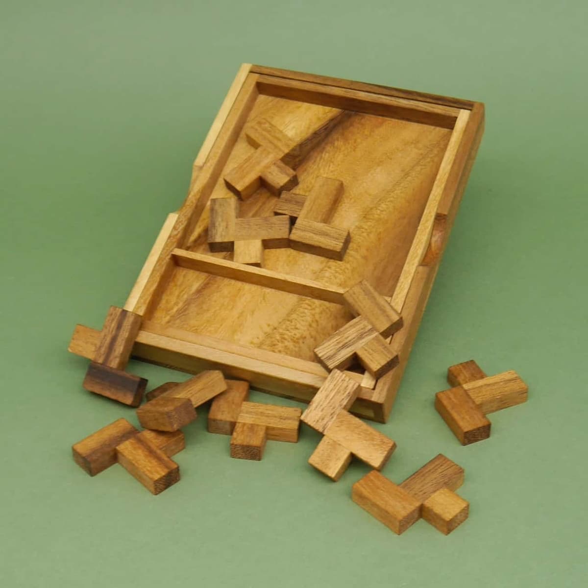 Schräg liegendes Holztablett, aus dem mehrere kleine L-Bausteine eines Denksport-Puzzles herausrutschen.