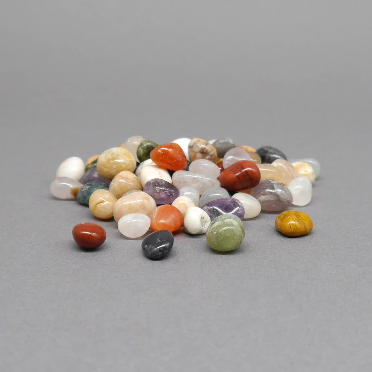 Polierte Ersatzsteine in verschiedenen Farben für Kalaha oder Mancala Bohnenspiele auf grauer Fläche.