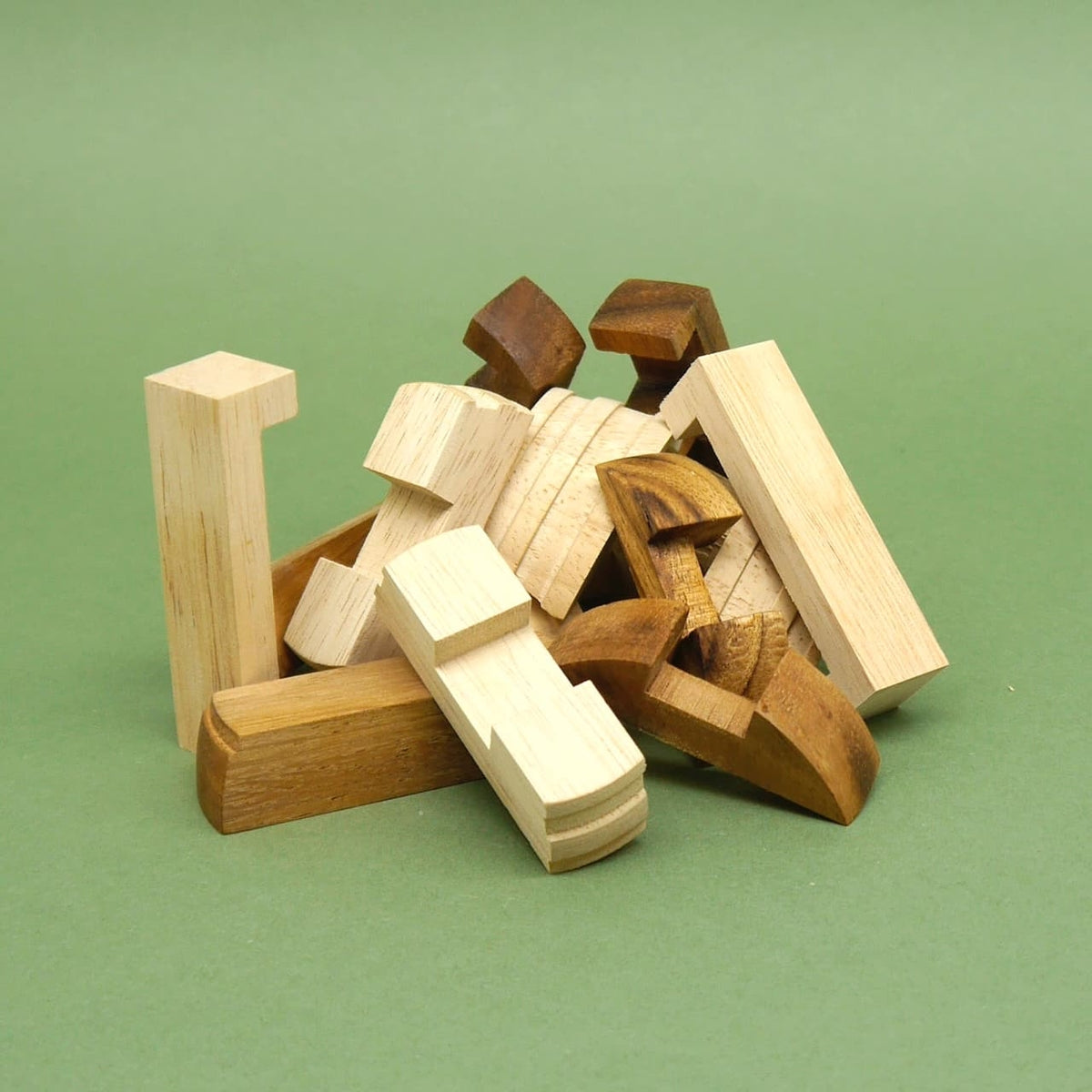Zerlegte Einzelteile des „Fass des Diogenes“ brain game 3D-Puzzles: unterschiedlich geformte Holzsteine des Spiels liegen ungeordnet auf grünem Untergrund.
