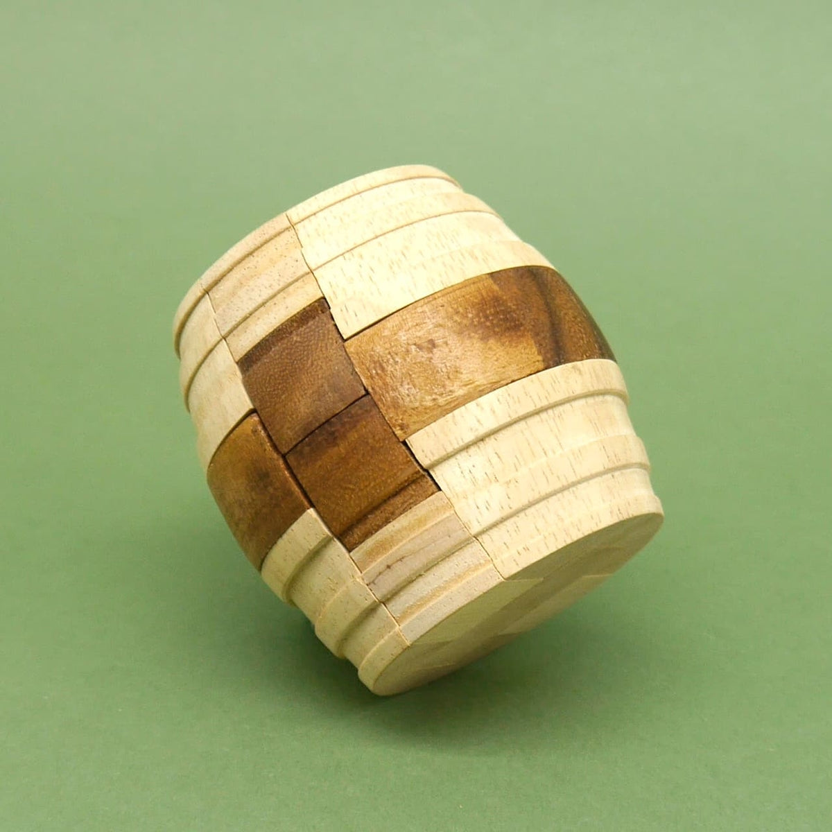 Komplett montiertes „Fass des Diogenes“ Knobelspiel: zweifarbiges Holzspiel für Denksport, seitlich gekippt vor grünem Hintergrund.