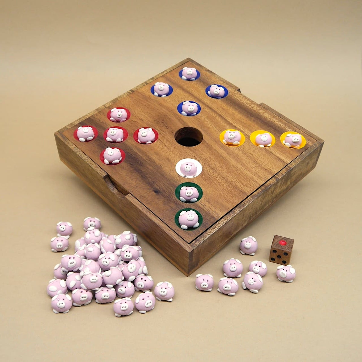 Quadratisches Holzbrett mit bunten Ringen, niedlichen Schweinchen-Figuren und Würfel – ein fröhliches Kinderspiel.