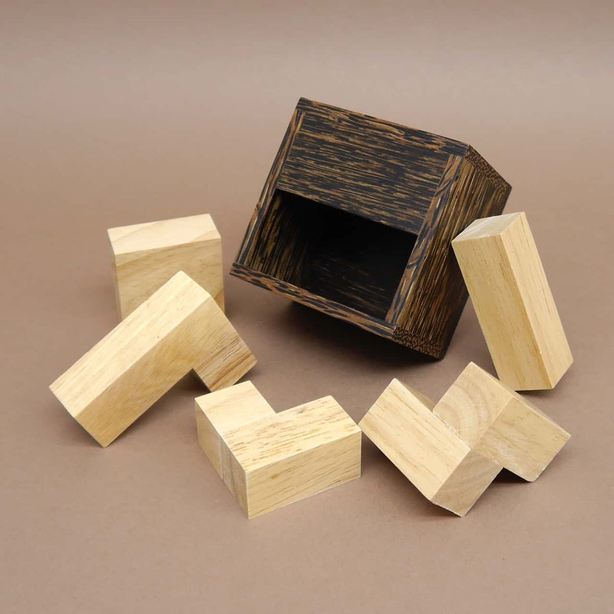 Offenes Holzkästchen und verstreute Soma-Klötzchen eines klassischen hölzernen geduldsspiel.