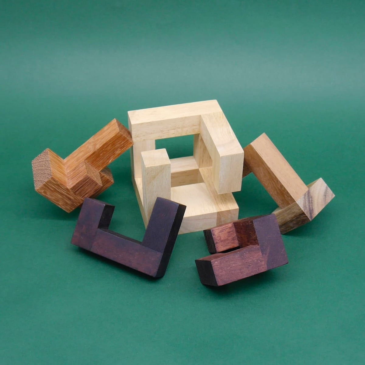 Zerlegtes 3D-Puzzle aus verschiedenen Holzarten liegt auf grünem Hintergrund – kreatives Logikspiel.