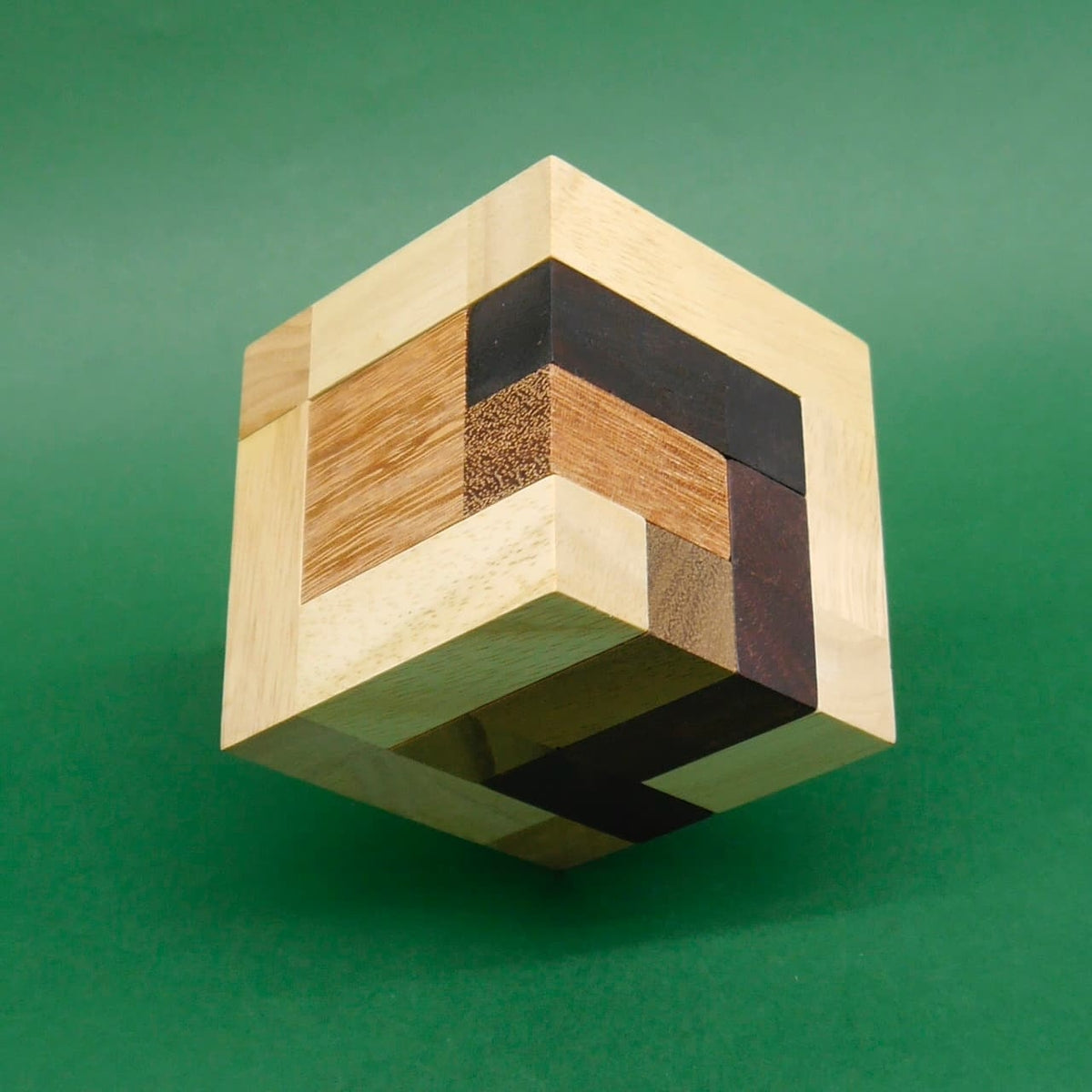 Schwebend fotografierter Holzwürfel aus hellen und dunklen Holzsegmenten – ideales Puzzle zum Knobeln.