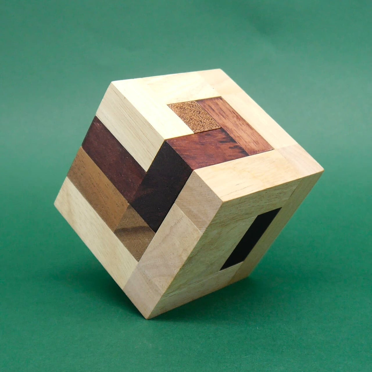 Vollständig zusammengesetztes Würfelpuzzle aus edlen Holzstreifen balanciert auf einer Ecke – spannendes Denkspiel.