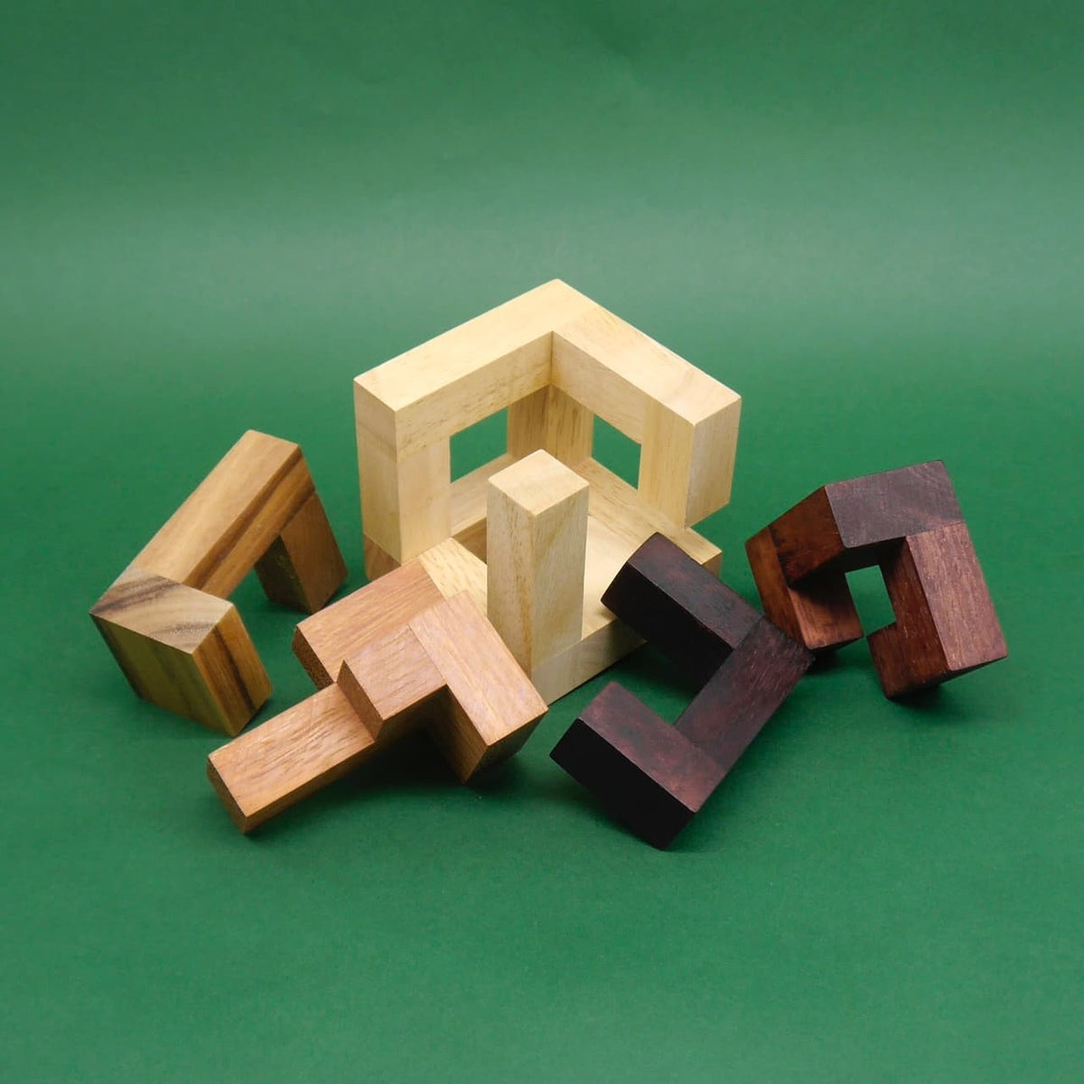 Teilweise gelöstes Holz-Knobelspiel mit Rahmen und Einzelteilen auf grünem Untergrund lädt zum Denksport ein.