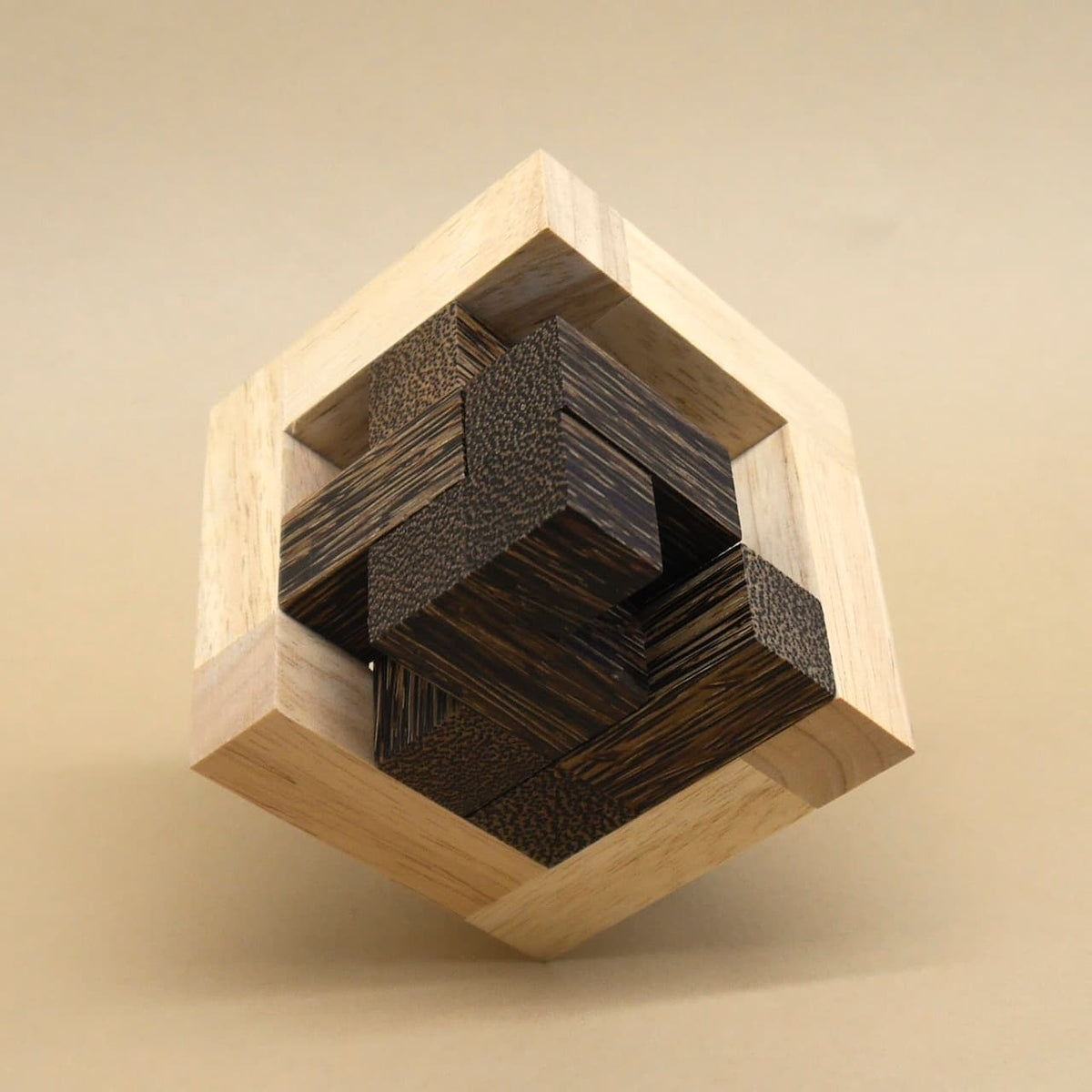 Zu einem Holzwürfel ineinander verschachtelte, helle und dunkle Holzstäbe bilden ein dreidimensionales Geduldspiel.