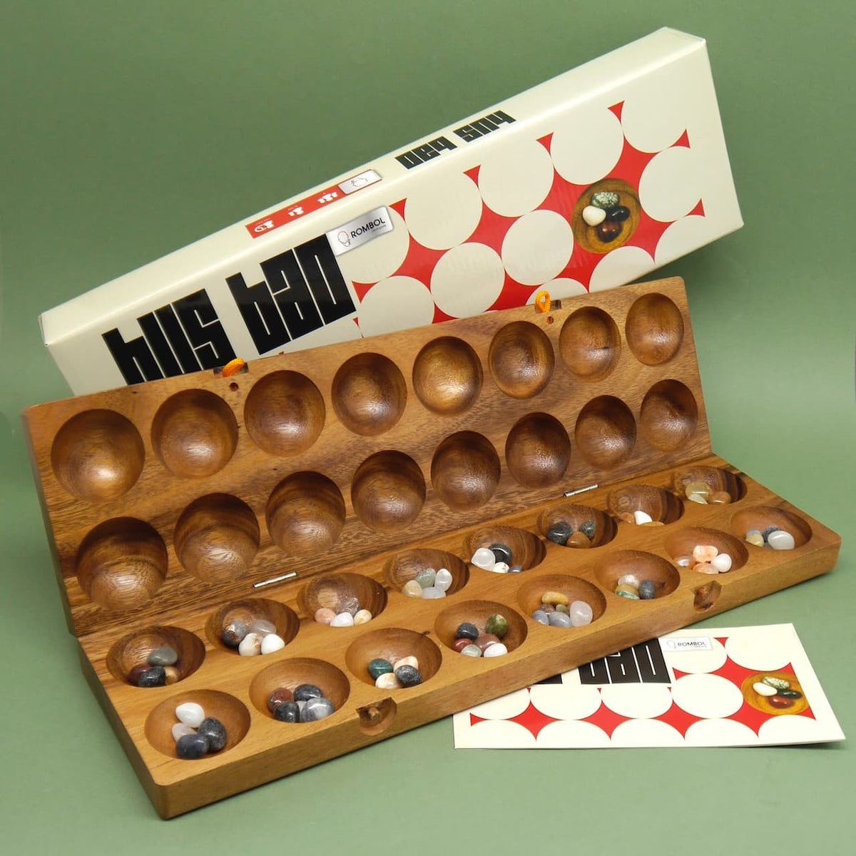 Mancala Bohnenspiel Hus Bao mit farbigen Edelsteinen in einem Holzbrett.