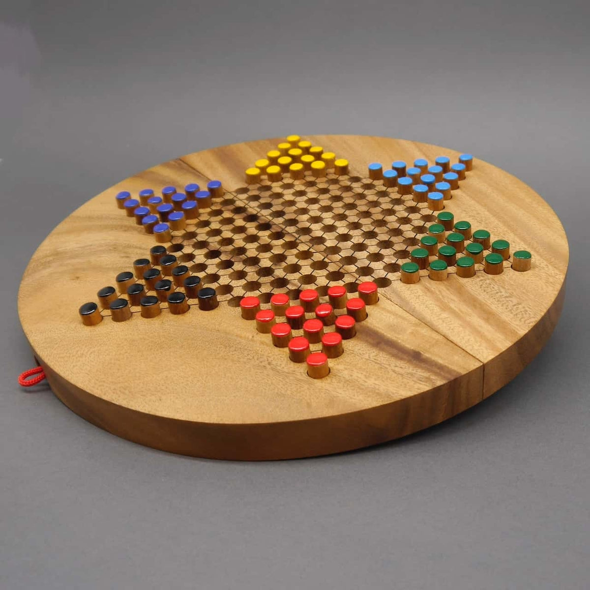 Ein rundes Halma-Brettspiel aus Holz in Sternform, vollständig aufgebaut mit farbigen Spielfiguren in Gelb, Blau, Grün, Rot und Schwarz. Die hochwertige Holzoberfläche und die präzise Anordnung der Löcher für die Spielfiguren unterstreichen das elegante De