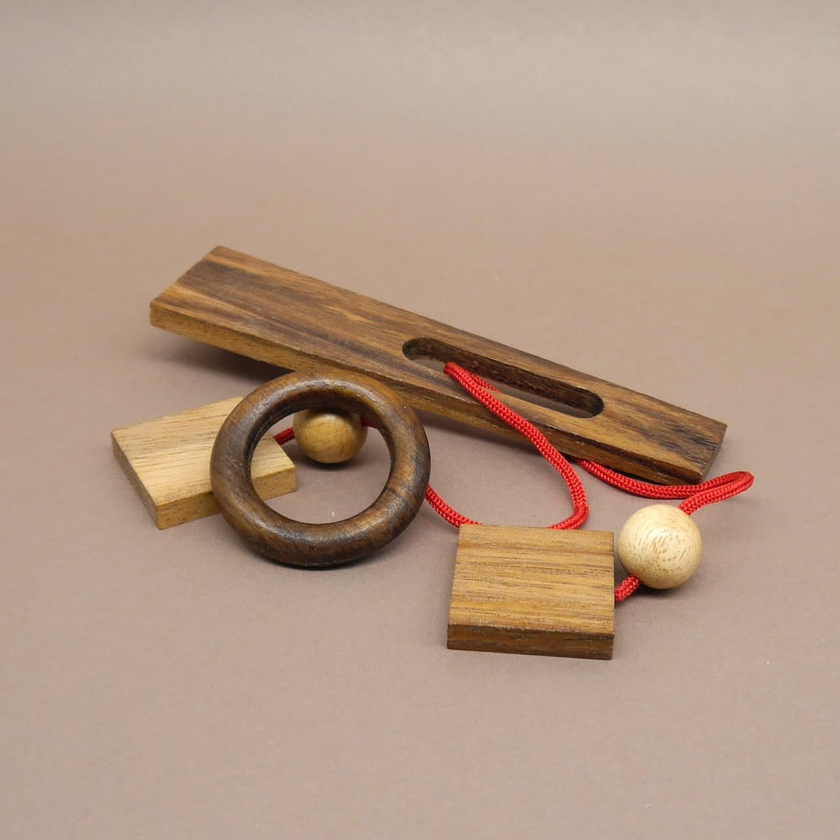 Holz-Geduldspiel mit roter Schnur, Holzring und Kugeln – ideal als kniffliges Denkspiel oder Geschenk.