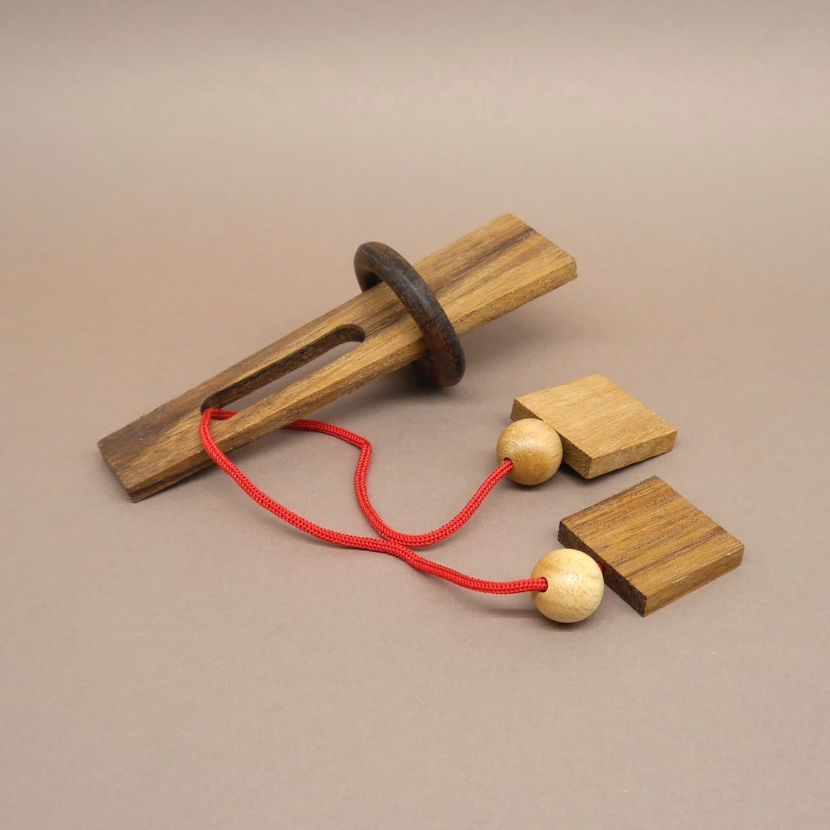 Anspruchsvolles Holzpuzzle mit Schnur, Kugeln und Holzring – ein Denkspiel für Knobelfreunde.