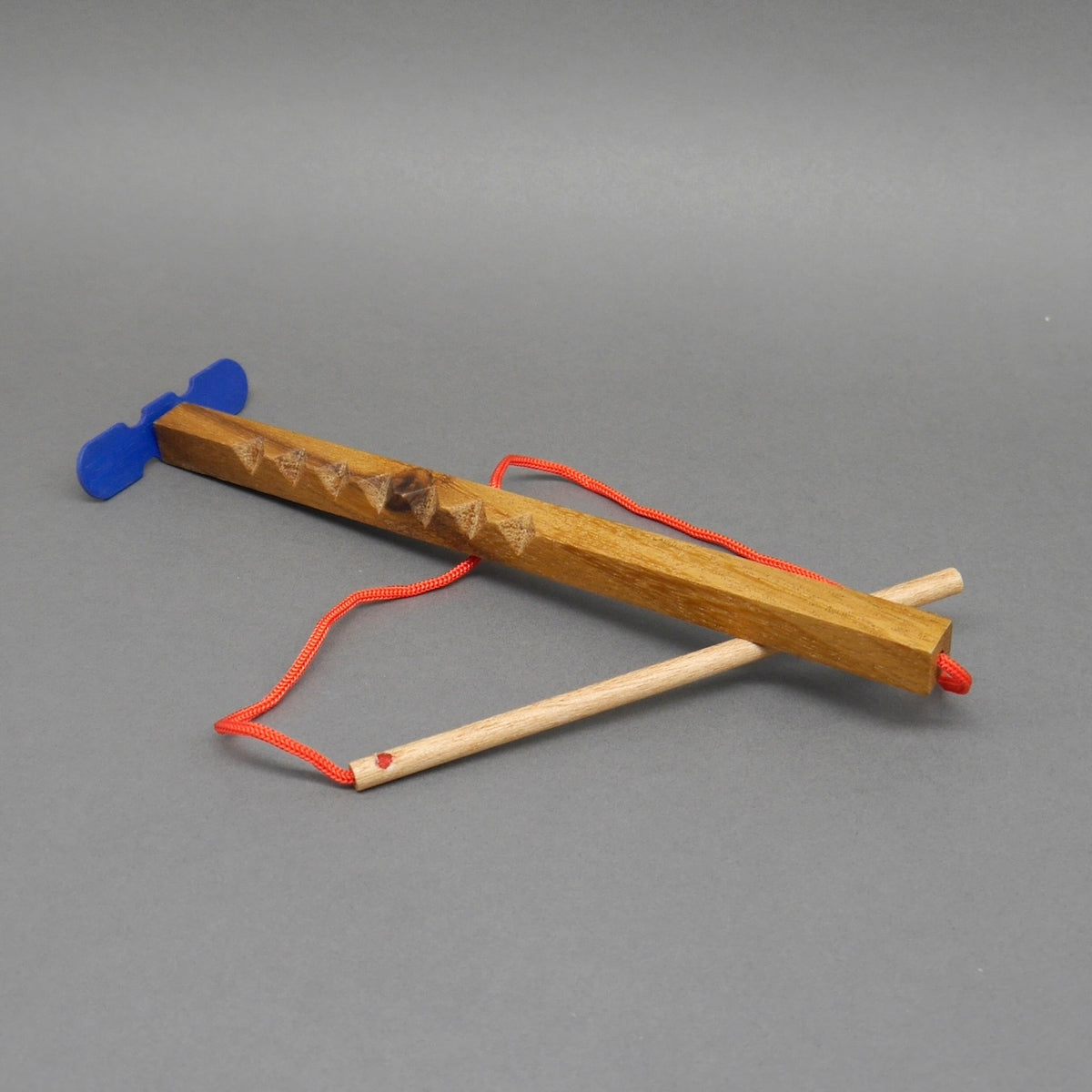 Hui‑Maschine Kinderspiel Propellerspiel Denkspiel: hölzerner Stab mit Rillen, roter Schnur und blauem Doppel‑Propeller.
