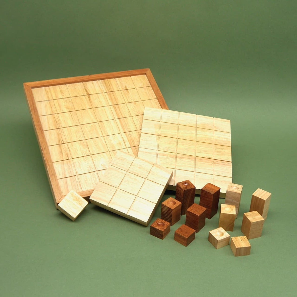 Indukto Holzspiel mit Raster-Brett, Platten und Holzklötzen für ein Taktikspiel für 2 Personen, auf grünem Untergrund.