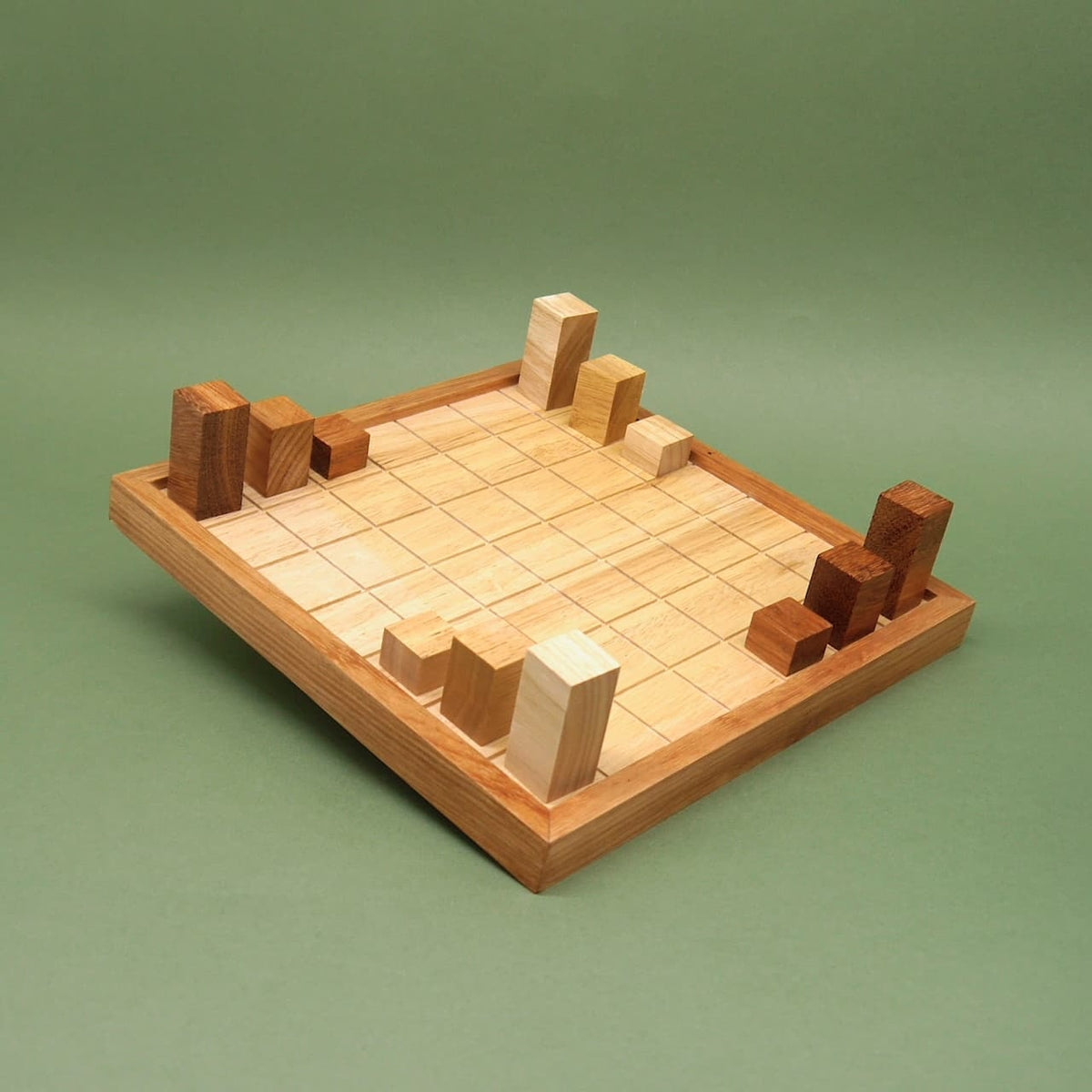 Aufgebautes Indukto Strategiespiel auf quadratischem Holzbrett; erste Klötze stehen an den Ecken des Rasters.