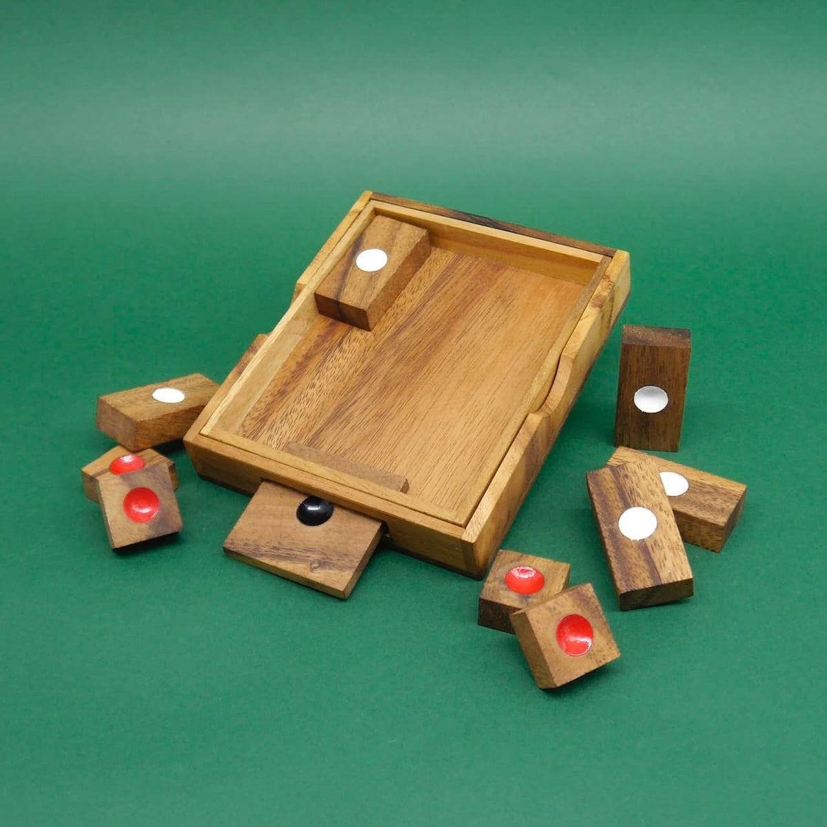 Aufgeklapptes Holz‑Geduldspiel mit leeren Spielflächen; umliegende Klötzchen zeigen weiße, rote und schwarze Markierungen.