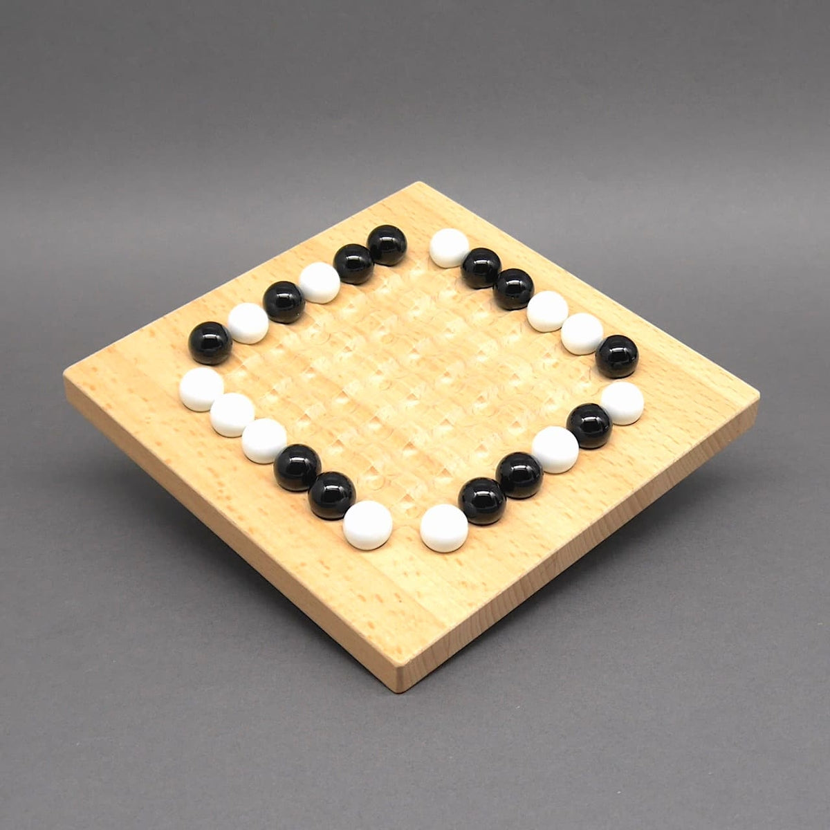 Holzbrettspiel mit schwarzen und weißen Kugeln, die auf einem quadratischen Raster angeordnet sind – perfektes Schiebespiel für strategisches Denken.
