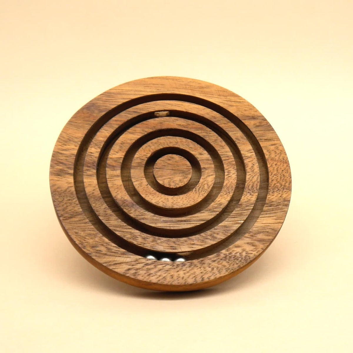Leicht nach hinten geneigtes rundes Holz‑Geschicklichkeitsspiel mit kreisförmigen Bahnen; mehrere Stahlkügelchen sammeln sich im äußeren Ring.