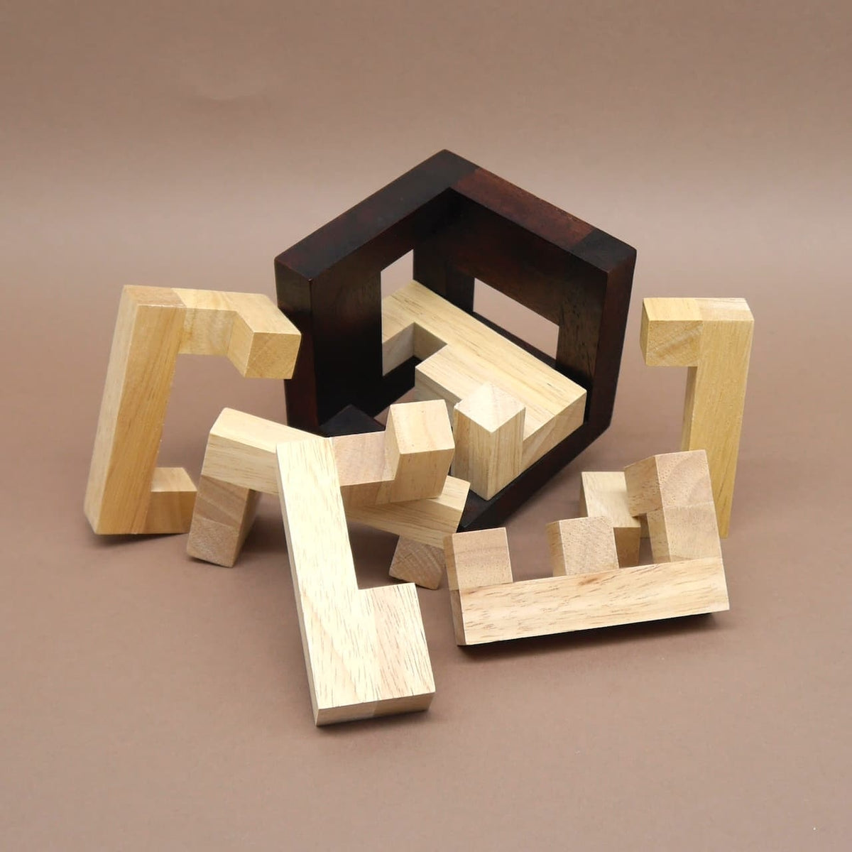 Ein Logikpuzzle aus hellen Holzbausteinen liegt halb zerlegt vor seinem dunklen offenen Rahmen.
