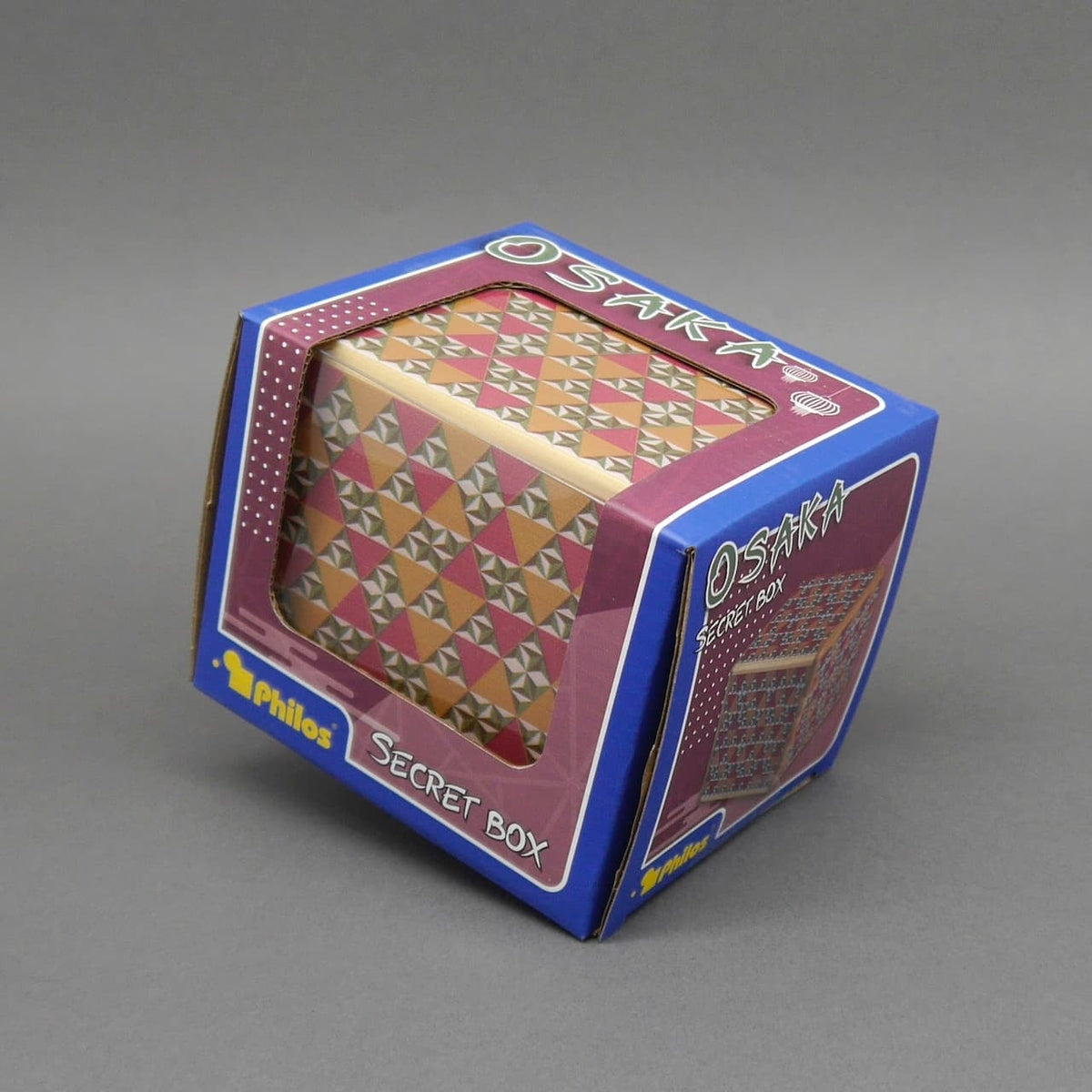 Farbige Geschenkverpackung in Würfelform mit geometrischem Muster, präsentiert in einer Schachtel mit der Aufschrift „Osaka Secret Box“