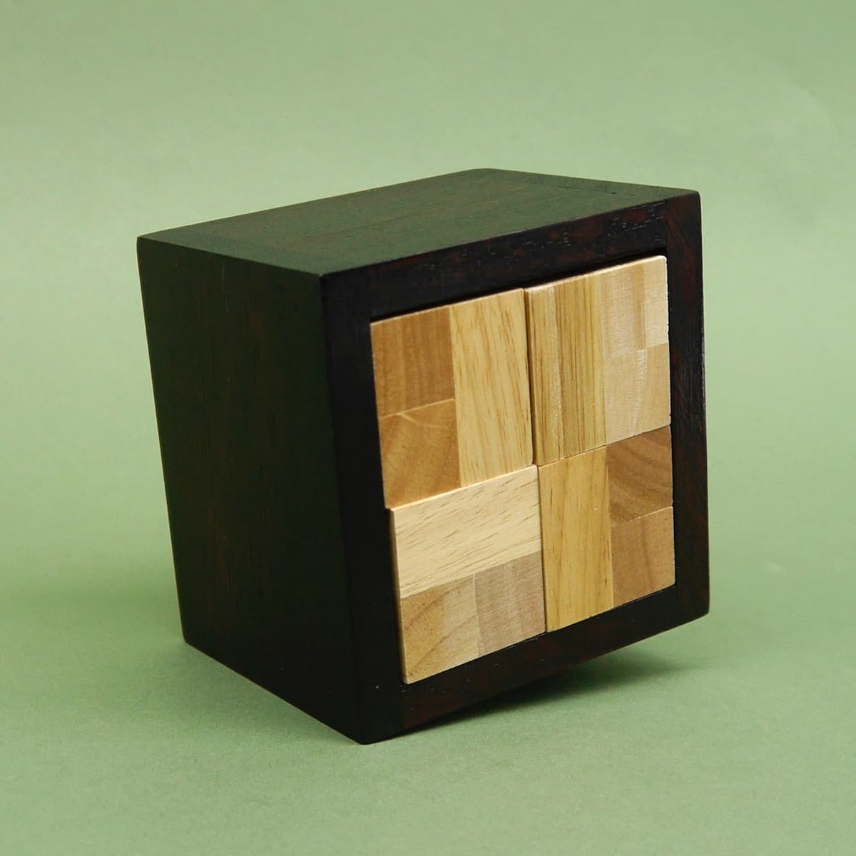 Geschlossener dunkler Holzwürfel mit symmetrischer Vorderseite aus vier hellen Blöcken – ein kompaktes Würfelpuzzle.