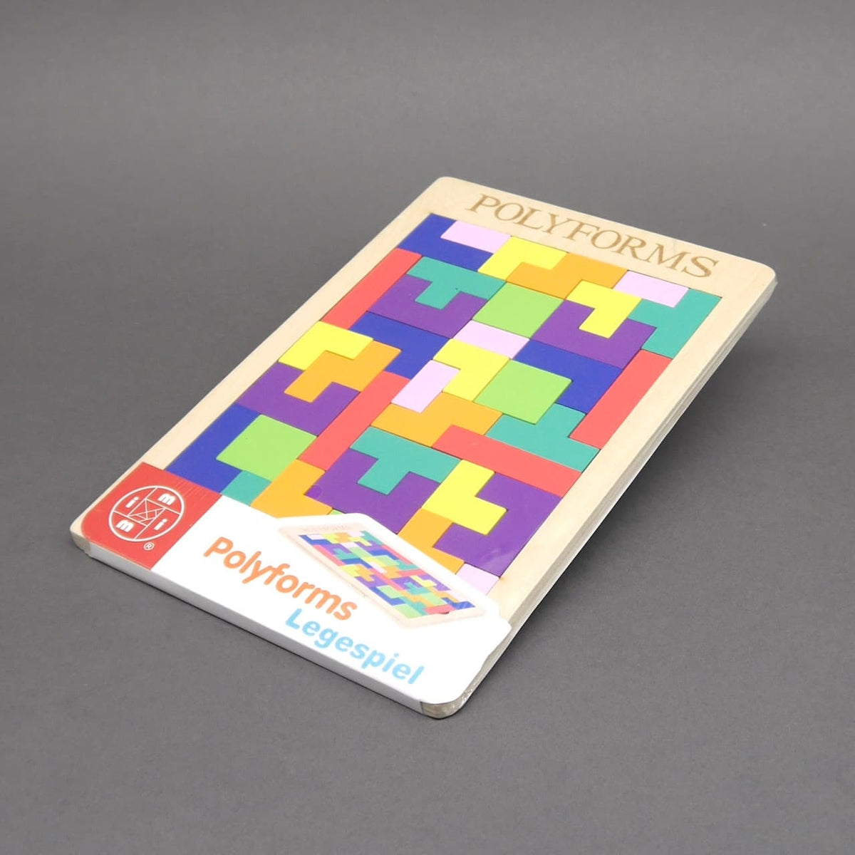 Vollständig gelegtes Polyforms-Legespiel mit bunten, passgenau eingefügten Formen in einem Holzrahmen. Unten auf dem Rahmen ist ein Aufkleber mit der Aufschrift „Polyforms Legespiel“ und einem Symbol der Marke.