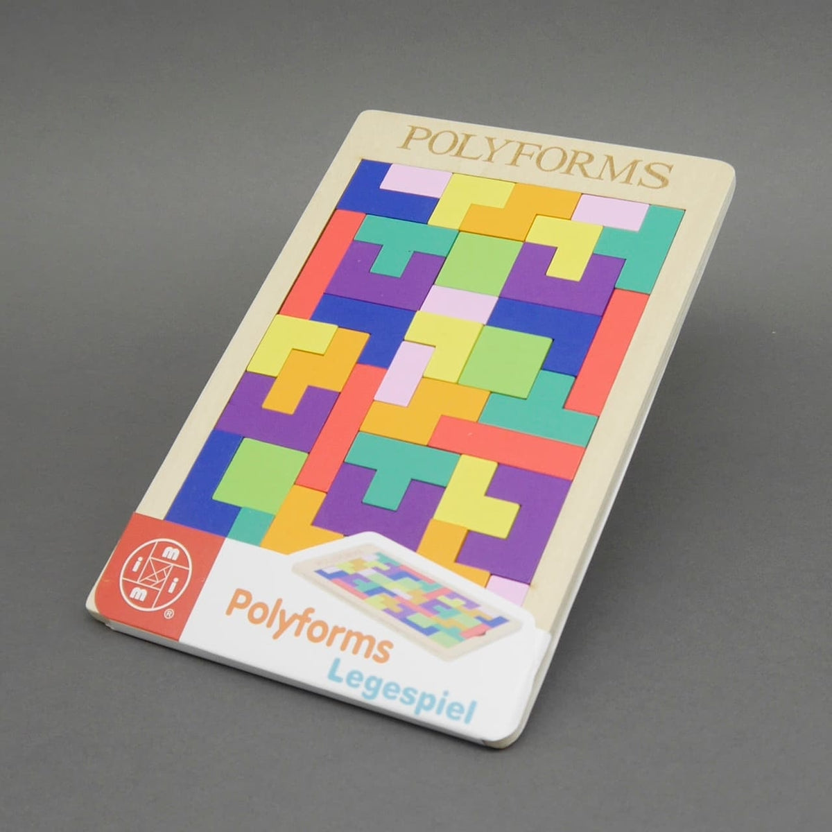 Ansicht eines komplett ausgefüllten Polyforms-Puzzles mit bunten Formen in einem Holzrahmen, leicht schräg aufgestellt. Der Aufkleber mit „Polyforms Legespiel“ ist ebenfalls sichtbar.