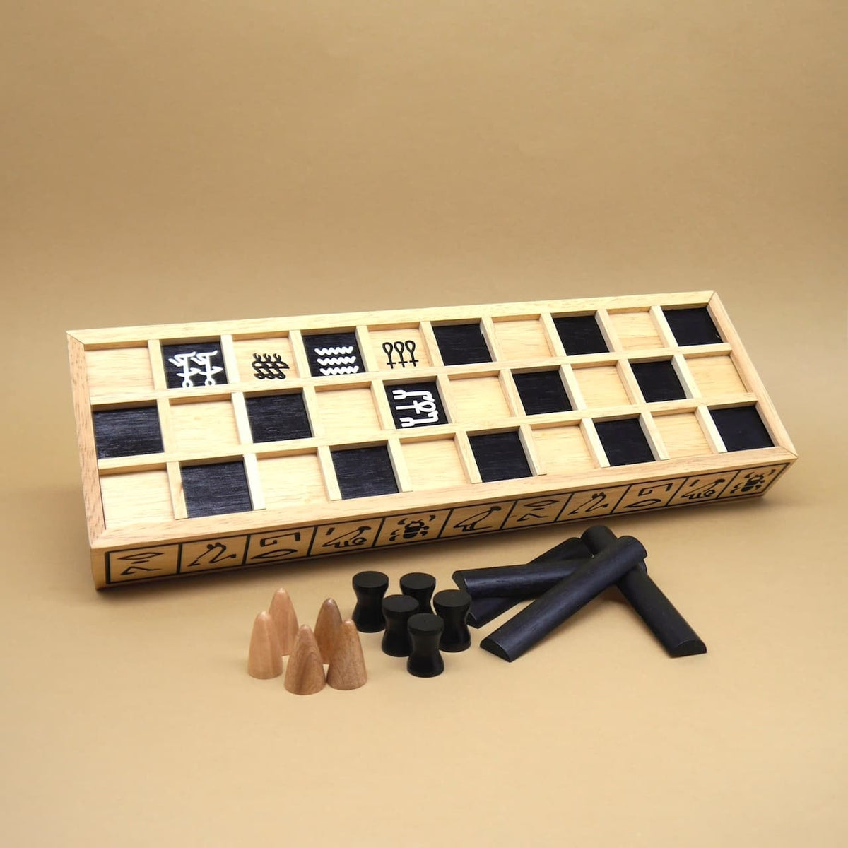 Holzbrett des ägyptischen Spiels Senet mit schwarz abgesetzten Feldern, Spielfiguren und Wurfstäben – traditionelles Wuerfelspiel vor beigem Hintergrund.