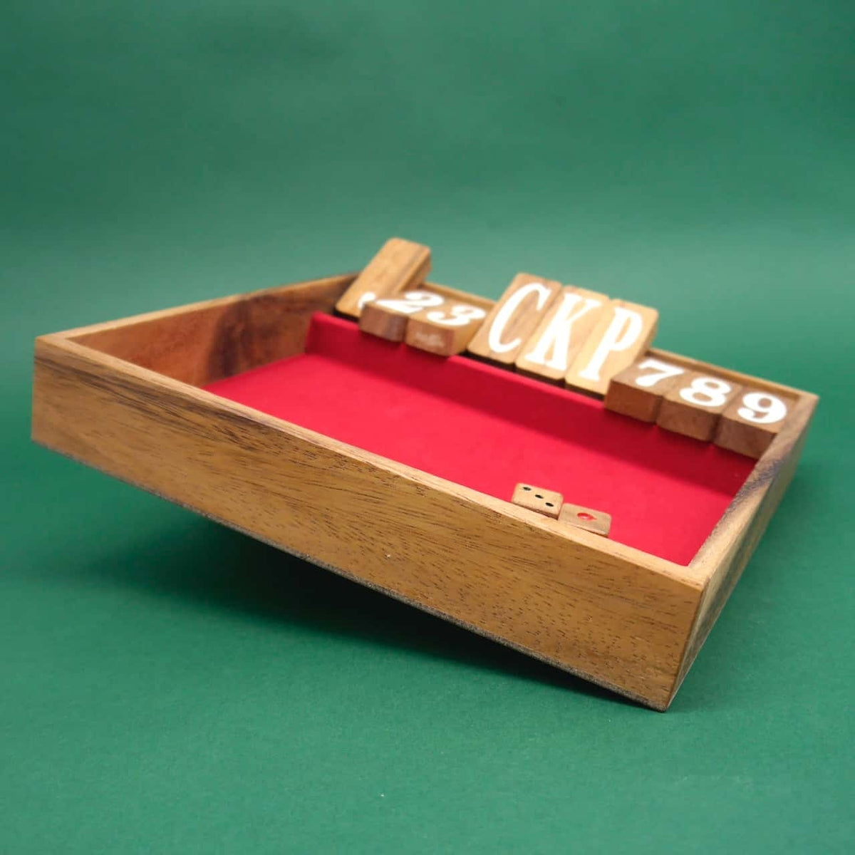 Ein klassisches Würfelspiel "Shut the Box" aus Holz mit roter Spielfläche. Die Klappdeckel sind von 1 bis 9 nummeriert und oben angeordnet. Neben der Box liegen zwei Holz-Würfel auf einem grünen Hintergrund.
