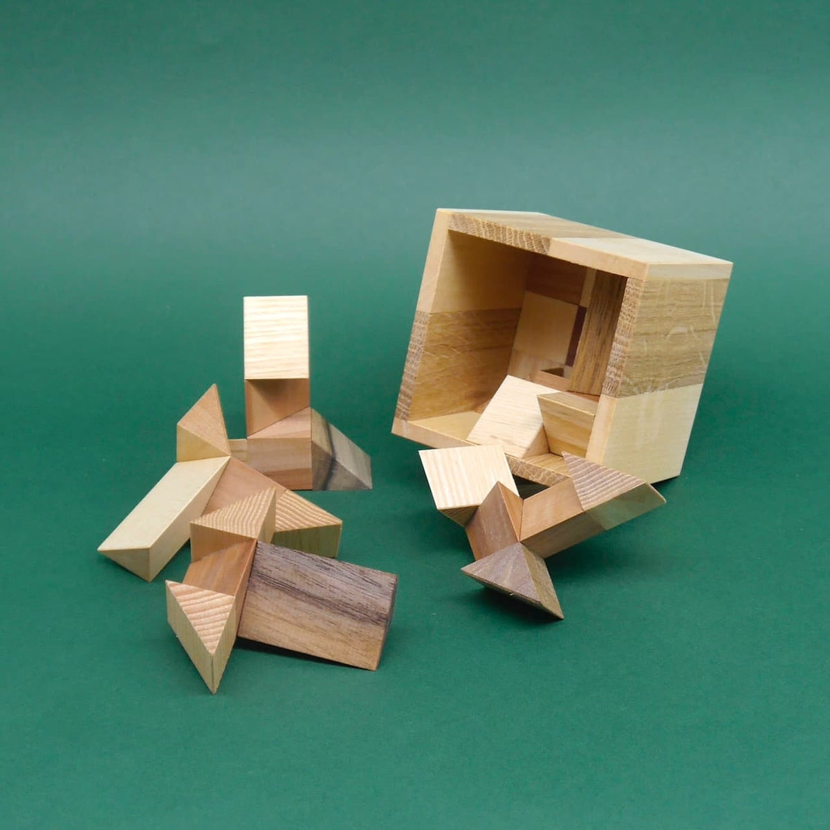 Geduldsspiel SixT: Holz-Packing-Puzzle mit geöffnetem Würfel und verstreuten, geometrischen Teilen.