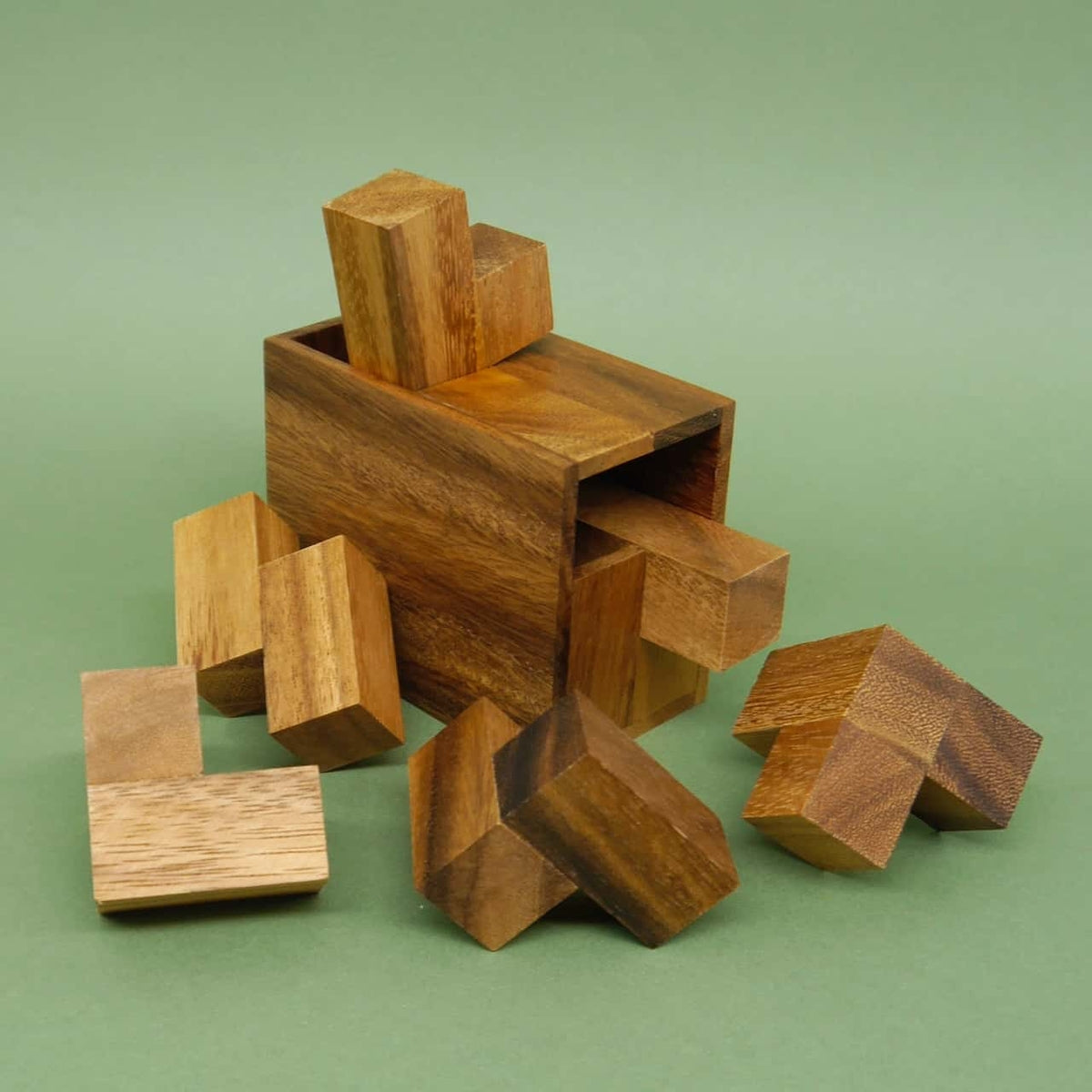 Zusammengebautes Holzpuzzle in Form einer rechteckigen Holzbox, umgeben von Puzzleteilen eines Geduldsspiels.