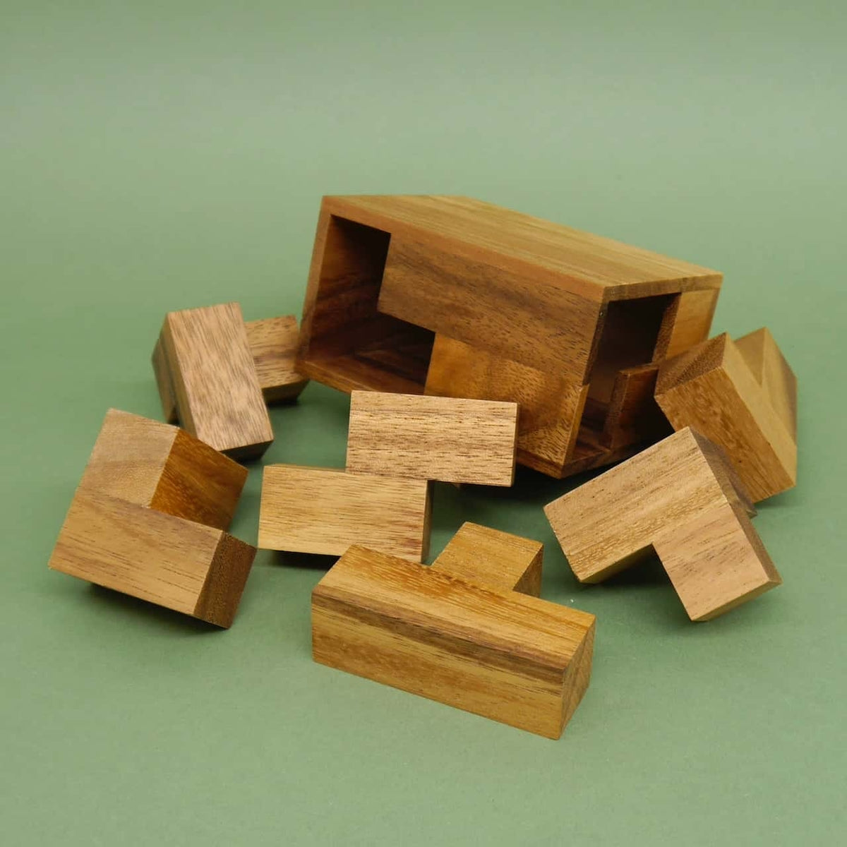 Einzelteile eines Holzpuzzles, verstreut vor der geöffneten Holzkiste – ein kniffliges Logikspiel.