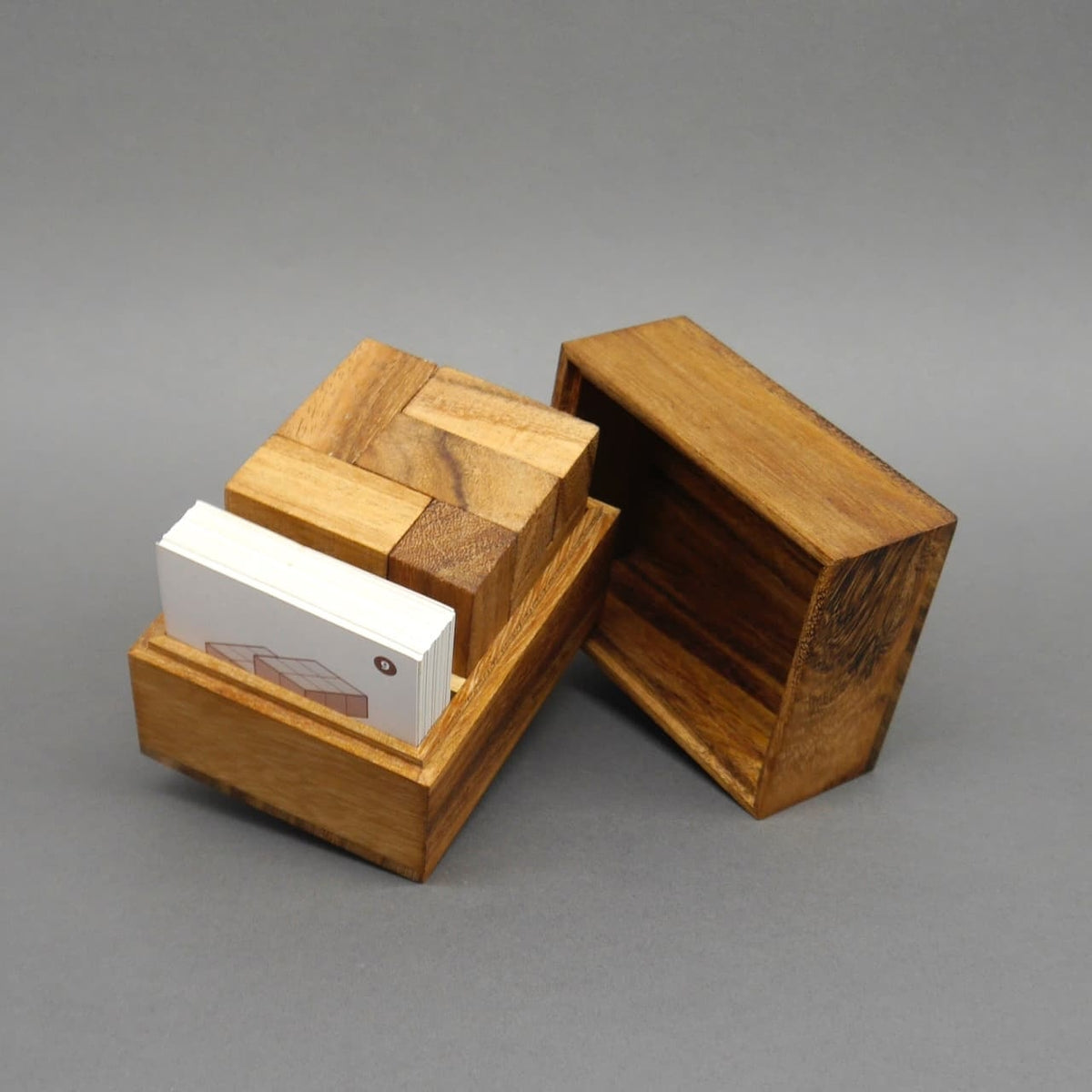 Geöffnete Holzbox mit 3D-Holzpuzzle und Karten, ein klassisches Knobelspiel aus Holz.