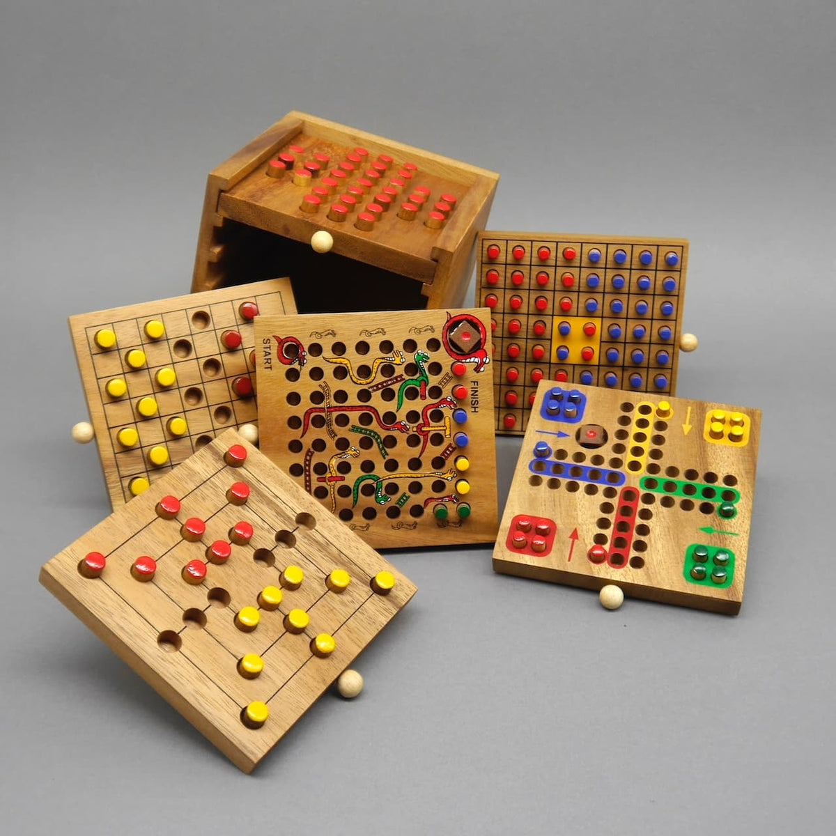 Sechs herausgenommene Spielbretter mit bunten Stiften zeigen ein vielseitiges Strategiespiele-Set aus Holz.