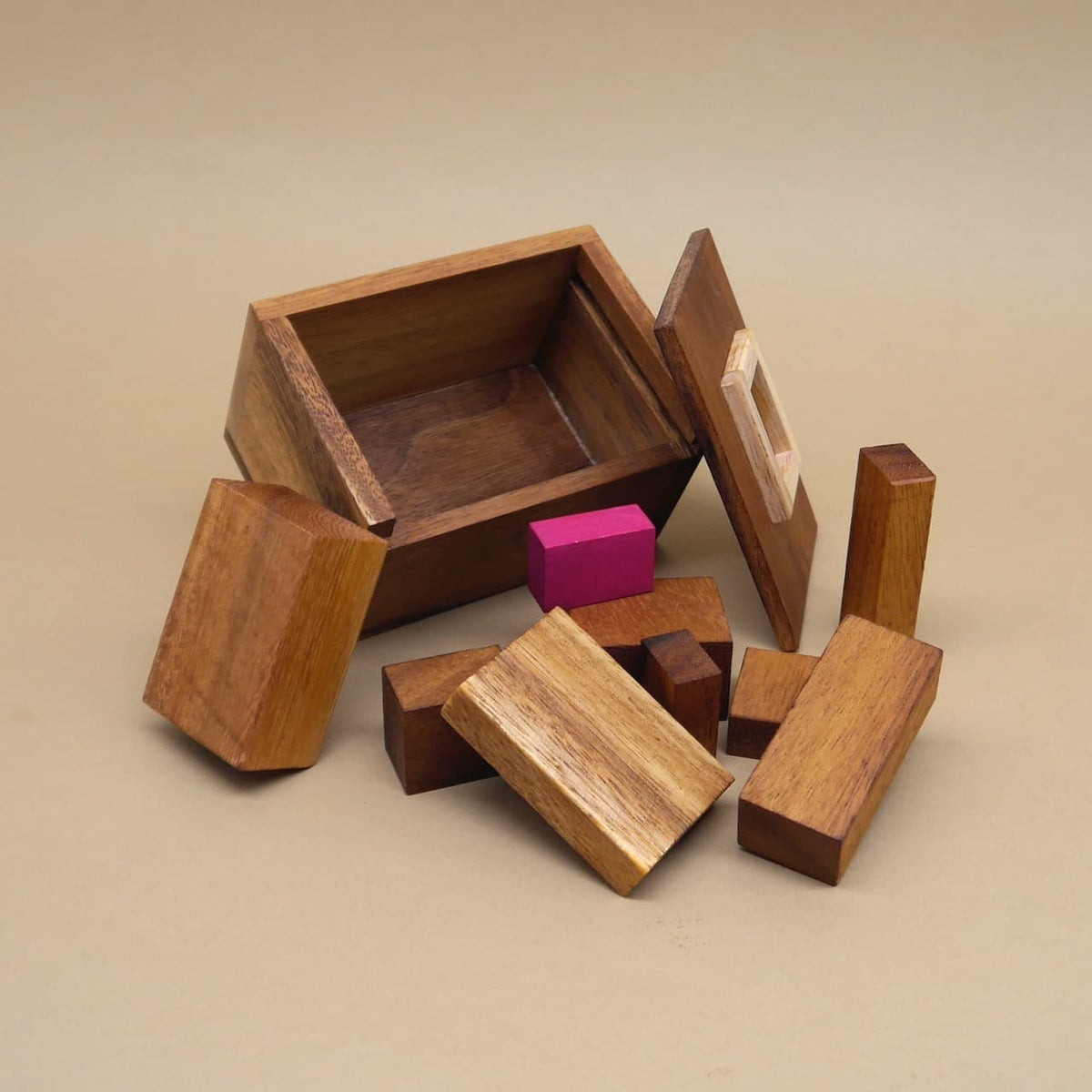 Geöffnete Teufelstein-Box, verstreute Holzbausteine und pinker Stein zeigen die Einzelteile des anspruchsvollen Logikpuzzle.