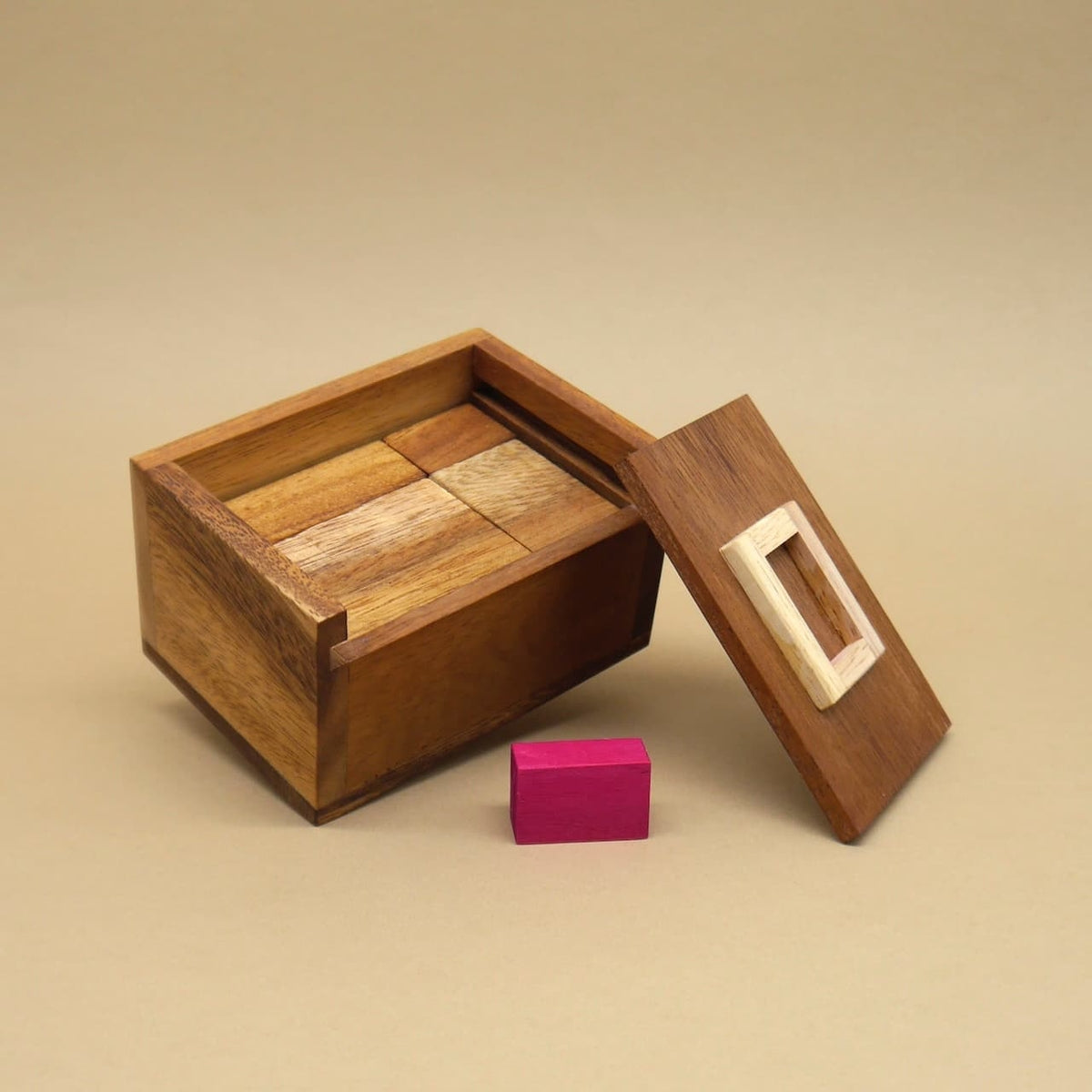 Teufelstein-Holzbox mit sauber einsortierten Holzklötzen; der pinke Stein liegt davor – ein minimalistischer Einblick in das hölzerne Braingame.
