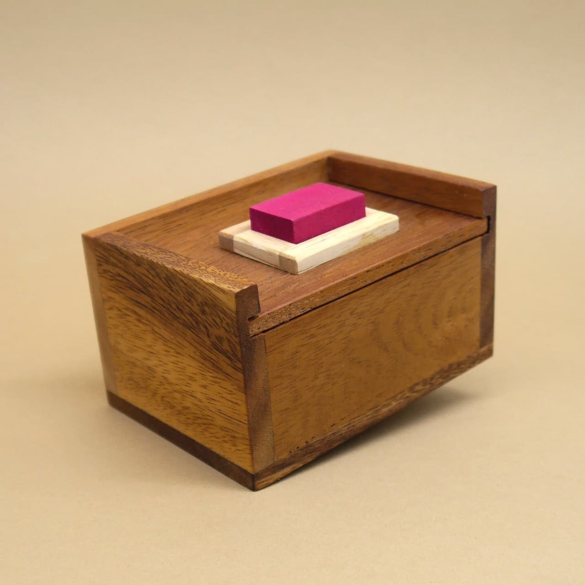 Fertig zusammengesetzte Teufelstein-Box mit pinkem Stein auf hellem Sockel, die Eleganz eines klassischen Holzpuzzle im Fokus.
